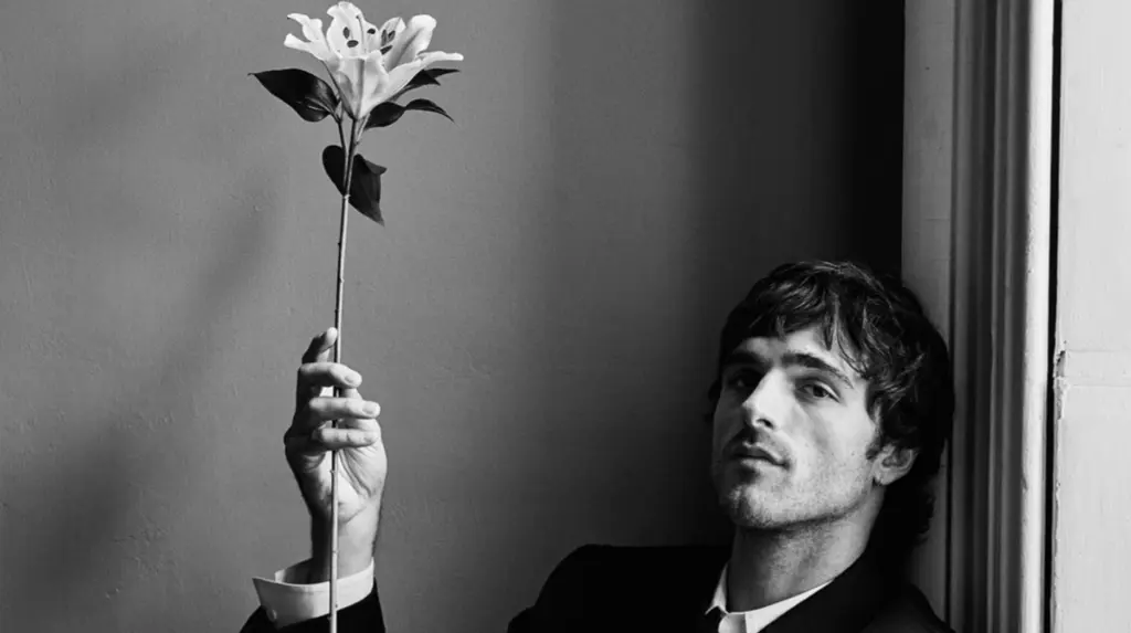 Bottega Veneta’nın siyah-beyaz estetikte, çiçek tutan modelle - Jacob Elordi - hazırlanan minimalist kampanya fotoğrafı.