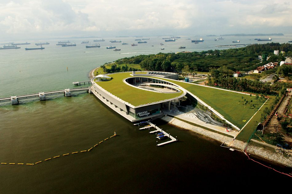 Singapur Marina Barrage’in yeşil çatılı sürdürülebilir mimarisi ve su yönetimi altyapısını gösteren havadan görünüm.