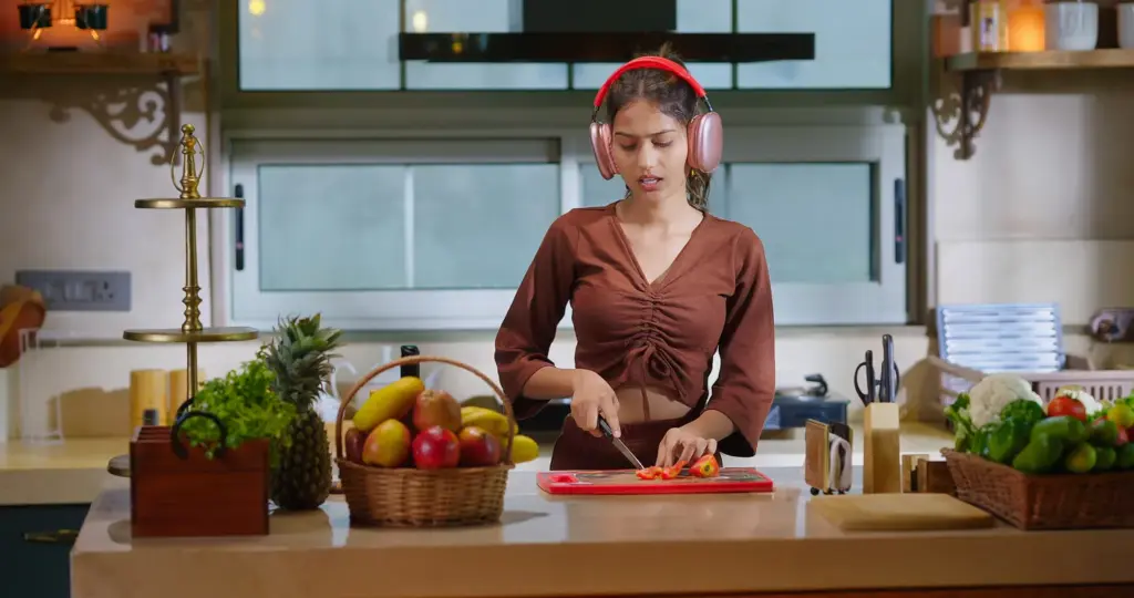 Gen Z’nin wellness alışkanlıklarını temsil eden mutfakta kulaklıkla sağlıklı yemek hazırlayan genç kadın.