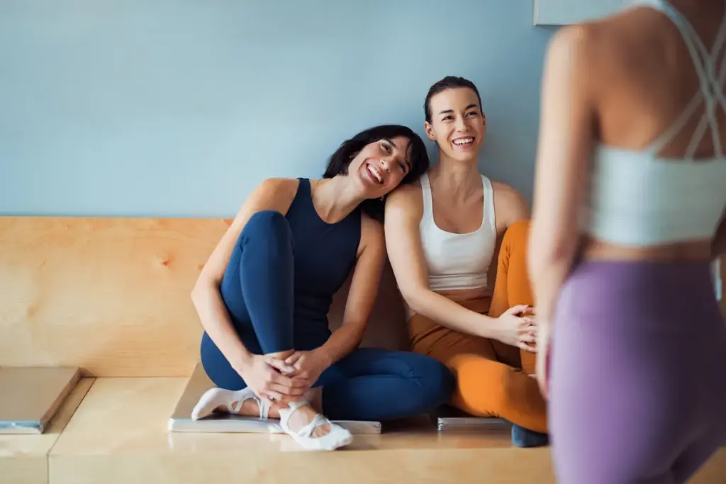 Toplulukla iyileşme trendini temsil eden spor salonunda yoga sonrası sohbet eden üç kadın.