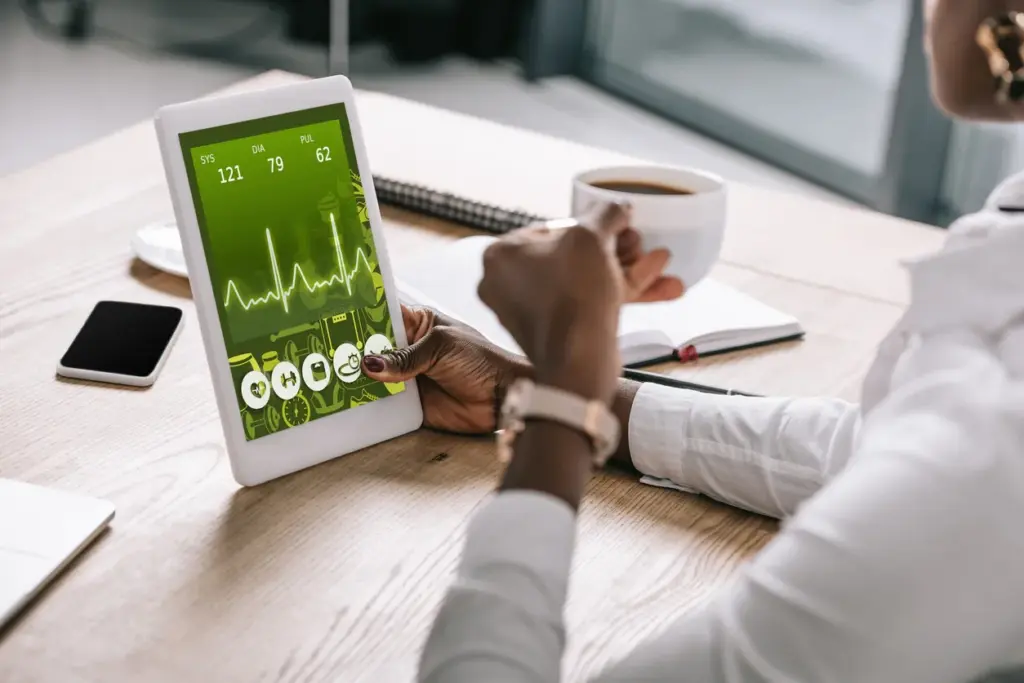 Yapay zekâ destekli wellbeing asistanını simgeleyen, tablet ekranında sağlık verilerini inceleyen ve kahve içen profesyonel.