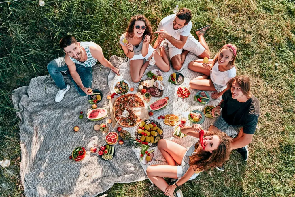 Z kuşağının wellness alışkanlıklarını temsil eden açık havada sağlıklı yiyeceklerle piknik yapan genç grup.
