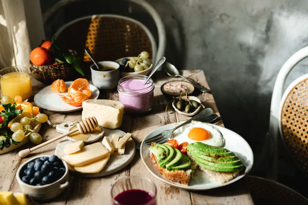 Biyobelirteç tabanlı beslenme trendini temsil eden avokadolu tost, yumurta, yoğurt, meyveler ve sağlıklı kahvaltı seçenekleriyle hazırlanan zengin beslenme masası.