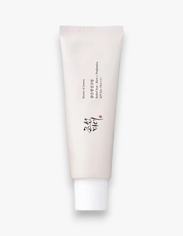 Aydınlık beyaz bir zeminde hafifçe gölgelenmiş, krem rengi, dik duran Beauty of Joseon Relief Sun: Rice + Probiotics SPF50+ PA++++ güneş kremi tüpü, markanın zarif kaligrafi logosu ve pirinç ile probiyotik içeriğini vurgulayan bilgileriyle dikkat çekiyor; cilt için etkili bir güneş koruması sunan bu ürün, beyaz, yivli bir kapakla tamamlanmıştır.