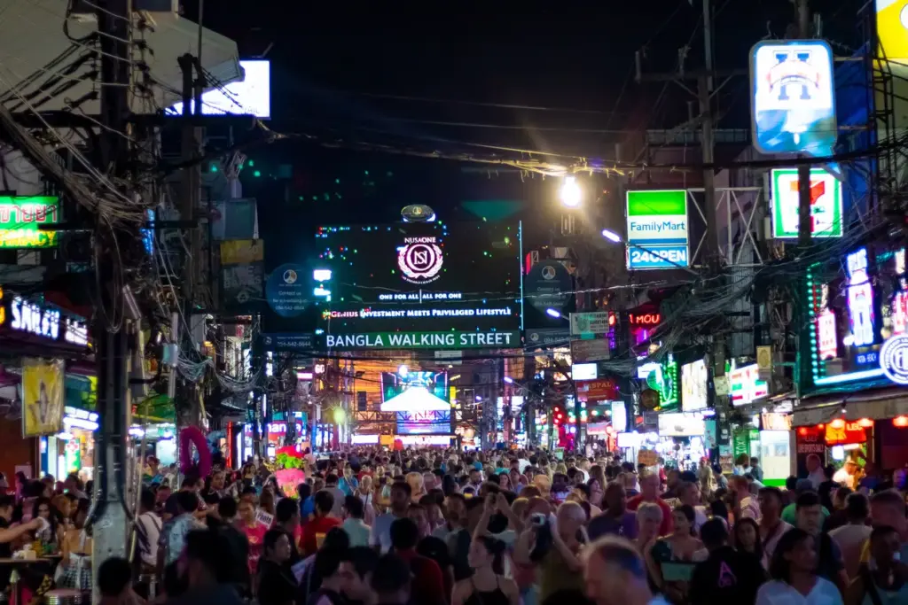 Phuket'in hareketli gece hayatının kalbi olan Bangla Yürüyüş Caddesi'nde, neon ışıklar ve renkli tabelalar altında yürüyen coşkulu kalabalıklar, adanın eğlence dolu yüzünü gözler önüne seriyor ve buranın öne çıkan gezilecek yerlerden biri olduğunu vurguluyor.