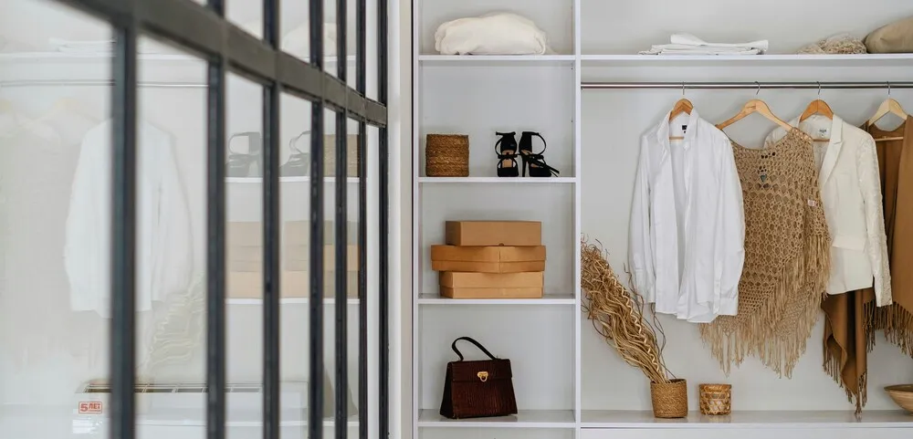 Nötr tonlarda düzenlenmiş kapsül gardırop; sade askılarda basic parçalar, raflarda minimalist aksesuarlar ve doğal dokulu detaylarla oluşturulmuş modern dolap düzeni.