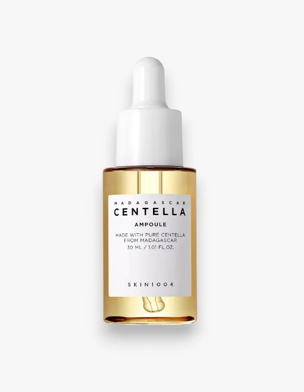 Beyaz kapaklı ve damlalıklı şeffaf bir cam şişede sunulan, altın sarısı renkteki SKIN1004 Madagaskar Centella Ampul serumu, üzerinde 30 ml hacmi ve saf Centella içeriği yazan beyaz etiketiyle cilt bakımı rutinleri için hazır bir şekilde duruyor.