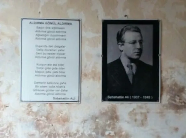 Sinop Cezaevi'nin duvarında yer alan Sabahattin Ali fotoğrafıyla ve Aldırma Gönül şiirinin sözleri.
