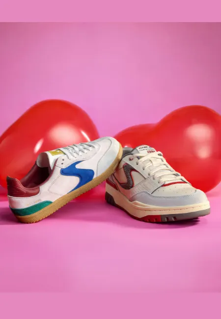“Pembe arka planda, kırmızı kalp balonları önünde konumlandırılmış iki sneaker ayakkabı.