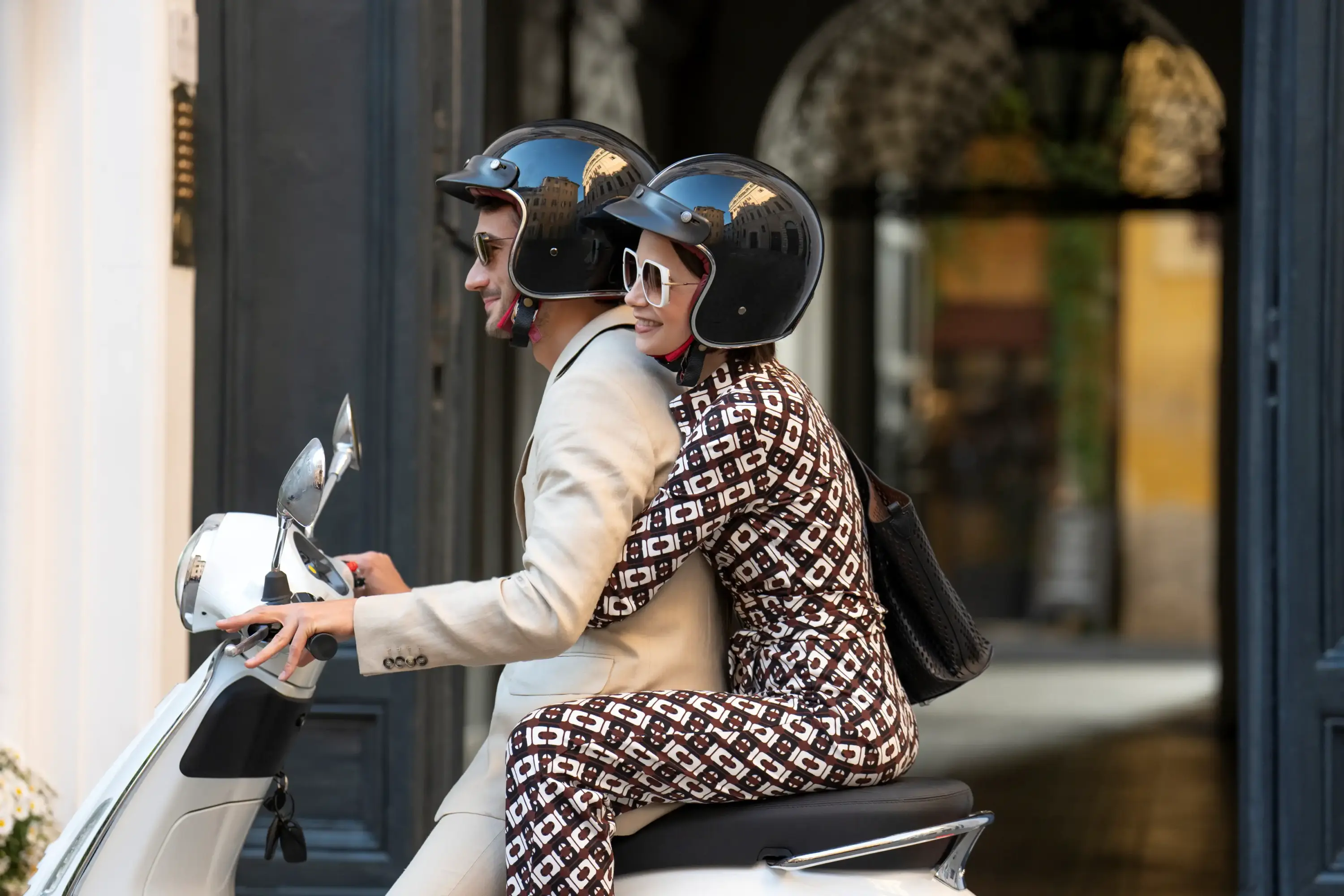 Emily in Paris dizisinde scooter üzerinde çekilen sahnede monogram desenli takım, retro kask ve Paris stiline gönderme.
