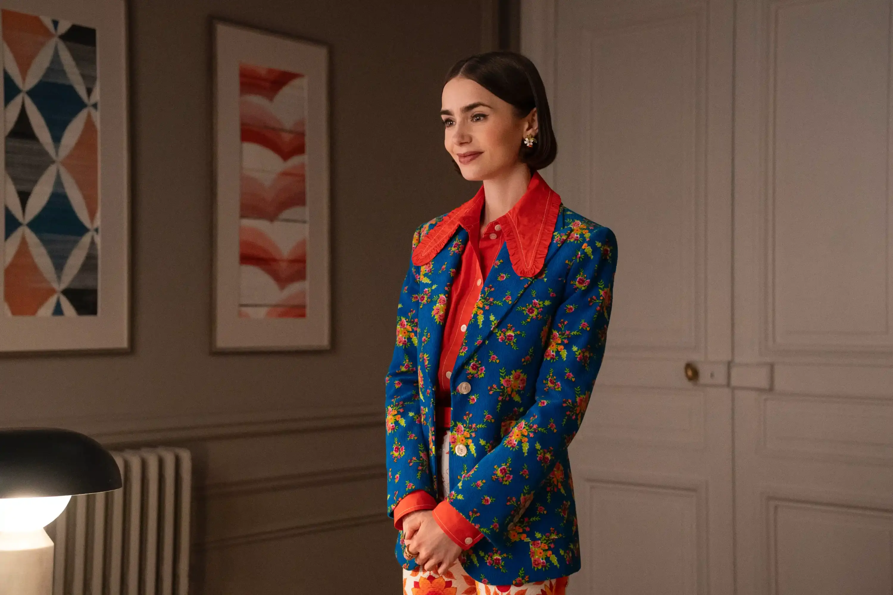 Emily in Paris dizisinde mavi çiçek desenli blazer, kırmızı gömlek ve retro ofis stilini yansıtan sofistike kombin.