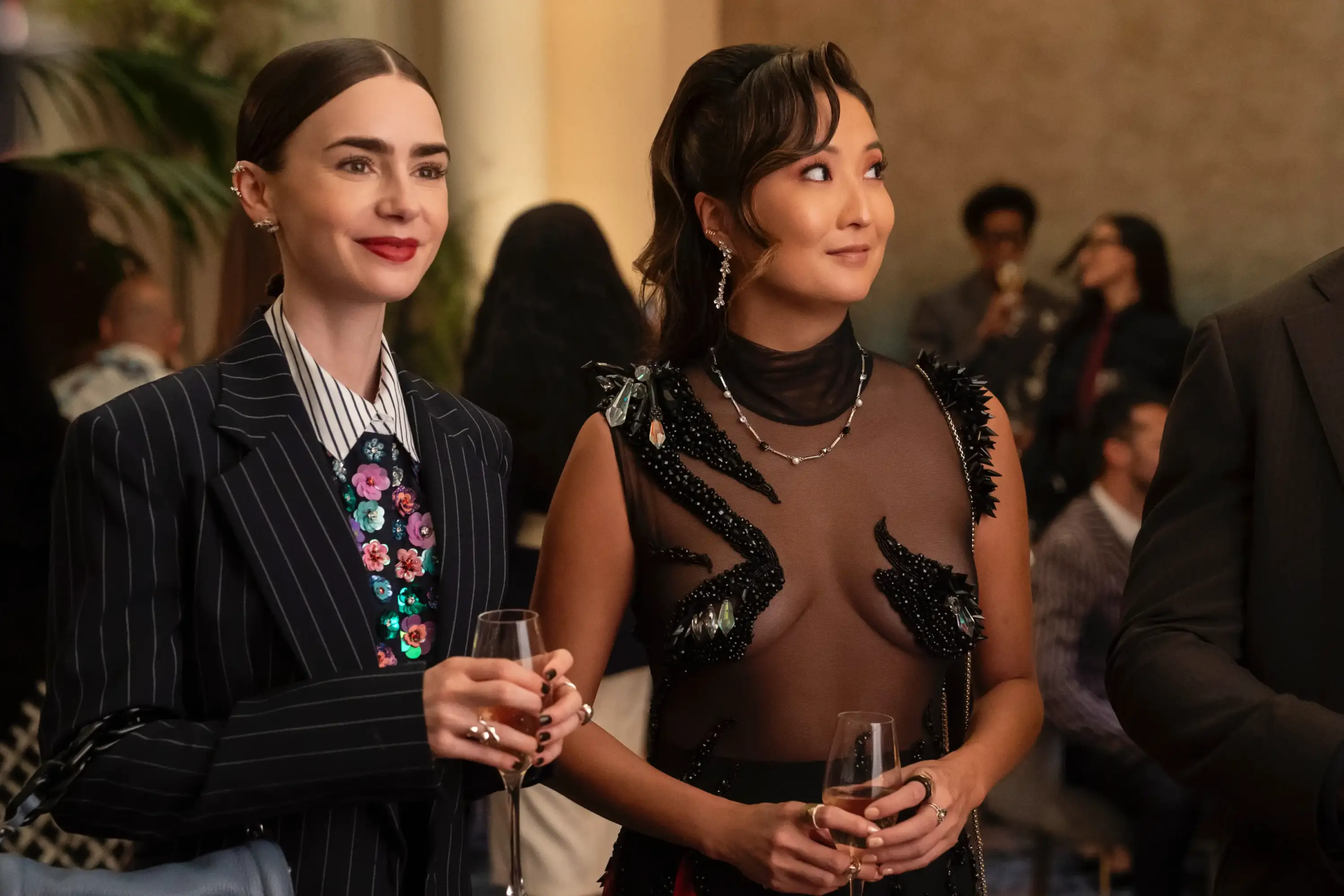 Emily in Paris dizisinde gece davetinde transparan detaylı siyah elbise ve çizgili takım elbise ile modern elegans.
