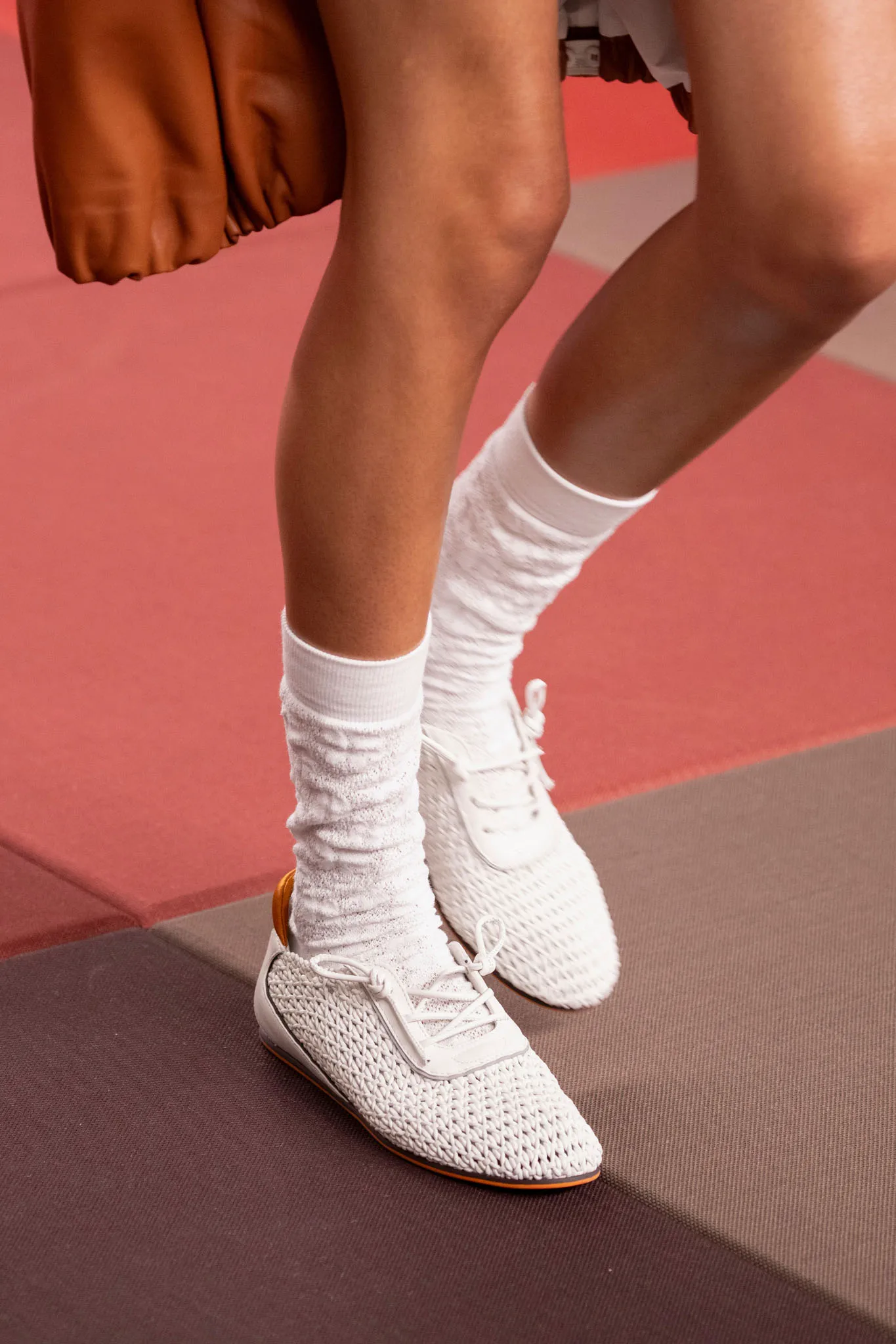 Fendi İlkbahar–Yaz 2025 koleksiyonundan görünüm; beyaz örgü dokulu slim sneaker’lar ve çorap stiliyle tamamlanan modern, hafif ve sportif yaz silüeti.