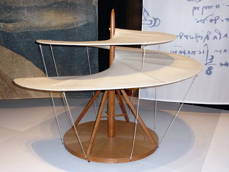 Leonardo da Vinci'nin dikey uçuşa yönelik çığır açan hava vidası icadının, ahşap orta direk, tripod benzeri taban ve ince gergi telleriyle birbirine bağlanmış, üst üste yerleştirilmiş iki geniş, açık renkli spiral kanattan oluşan detaylı bir sergi modeli.