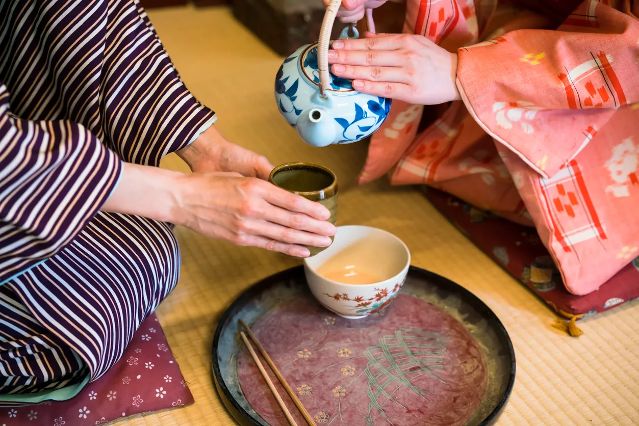 Kyoto’daki Toei stüdyolarında samuray döneminden kalma bir evde tatami üzerinde kimono giymiş iki kadının çay hazırlığı