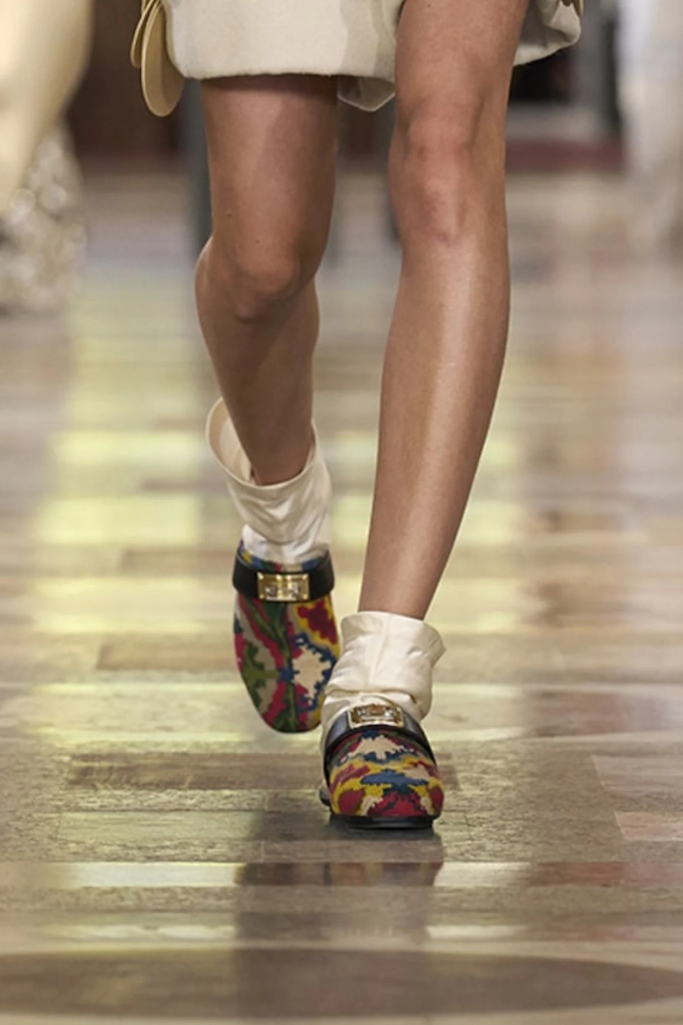 Louis Vuitton İlkbahar–Yaz 2026 koleksiyonundan podyum görünümü; nakışlı loafer ayakkabılar, çorap detayı ve el işçiliği vurgusuyla öne çıkan sofistike ve eklektik silüet.