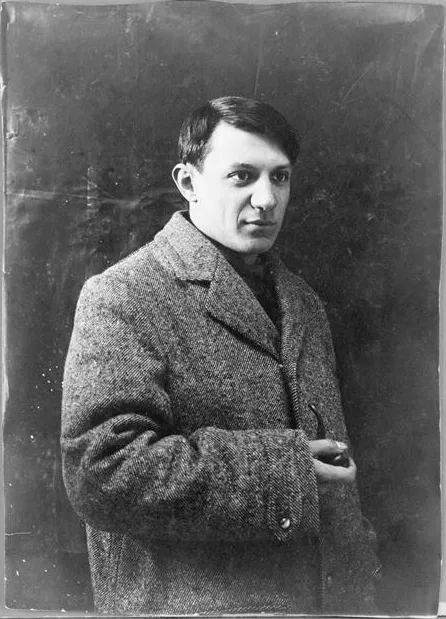 Sanatçı Pablo Picasso'nun siyah beyaz bir stüdyo fotoğrafı olan bu tarihi portrede, genç sanatçı, kısa kesilmiş saçları, koyu renkli tüylü bir palto içinde, sağ elinde piposuyla doğrudan izleyiciye yönelmiş kararlı bir bakışla duruyor.