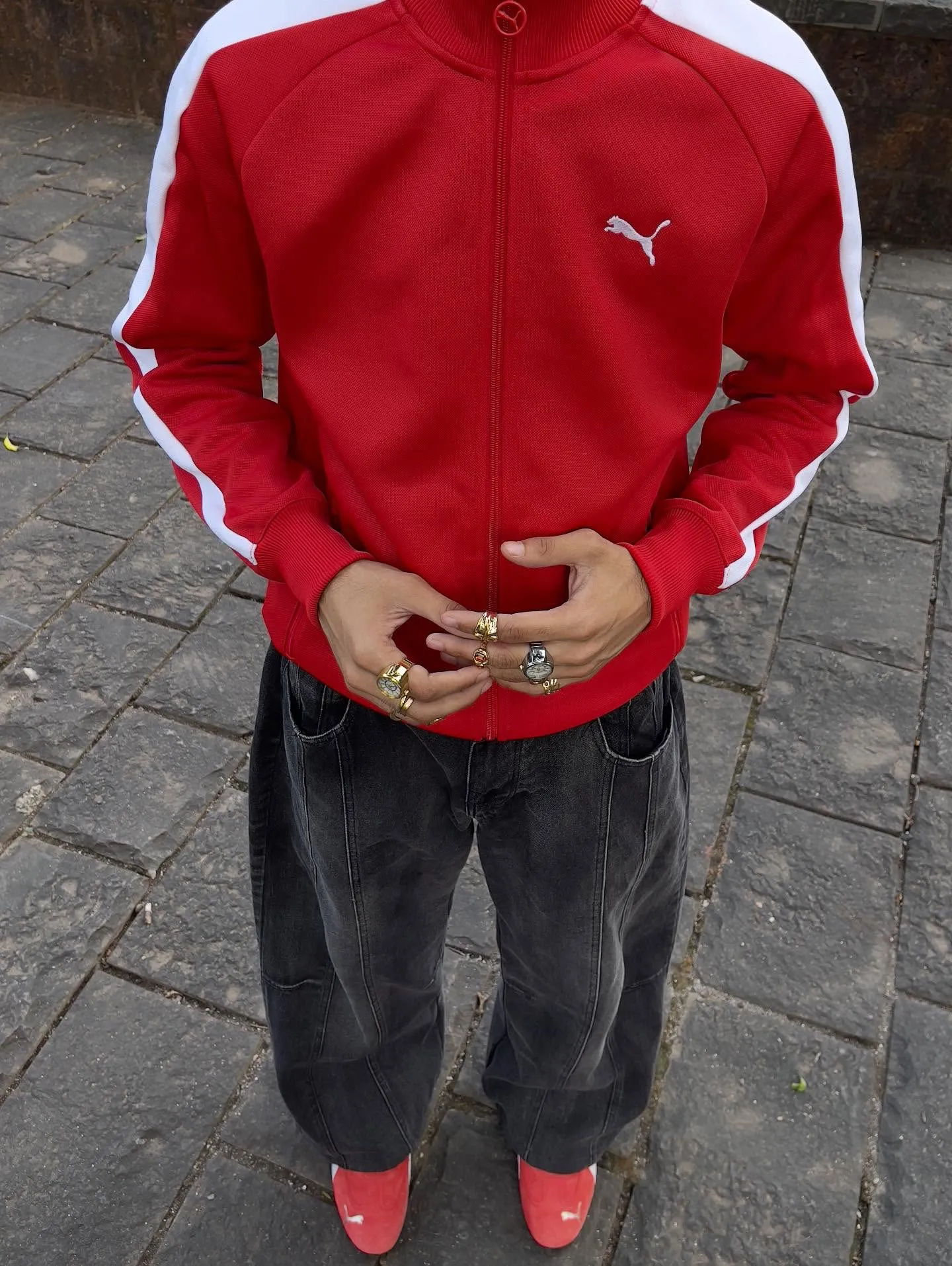 Puma Speedcat sneaker, kırmızı fermuarlı ceket ve koyu renk pantolonla tamamlanan sportif sokak stili kombiniyle alçak taban sneaker trendini yansıtıyor.