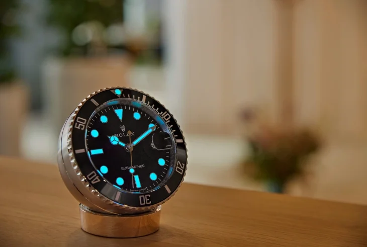 Rolex Submariner Date masa saatinin karanlıkta fosforlu ışığıyla görünen kadranı; siyah zemin ve parlak fosfor detayları.