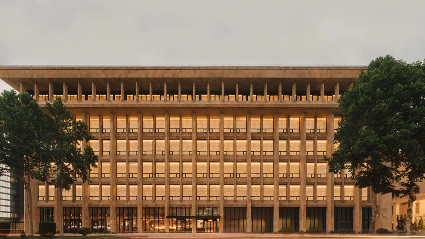 Tbilisi'deki Telegraph Tbilisi Hotel, akşam ışıklarıyla parlayan pencere sıraları ve üst katlarındaki dikkat çekici sütunlarıyla modern taş cephesini sergileyen geniş bir yapı olarak görülüyor.
