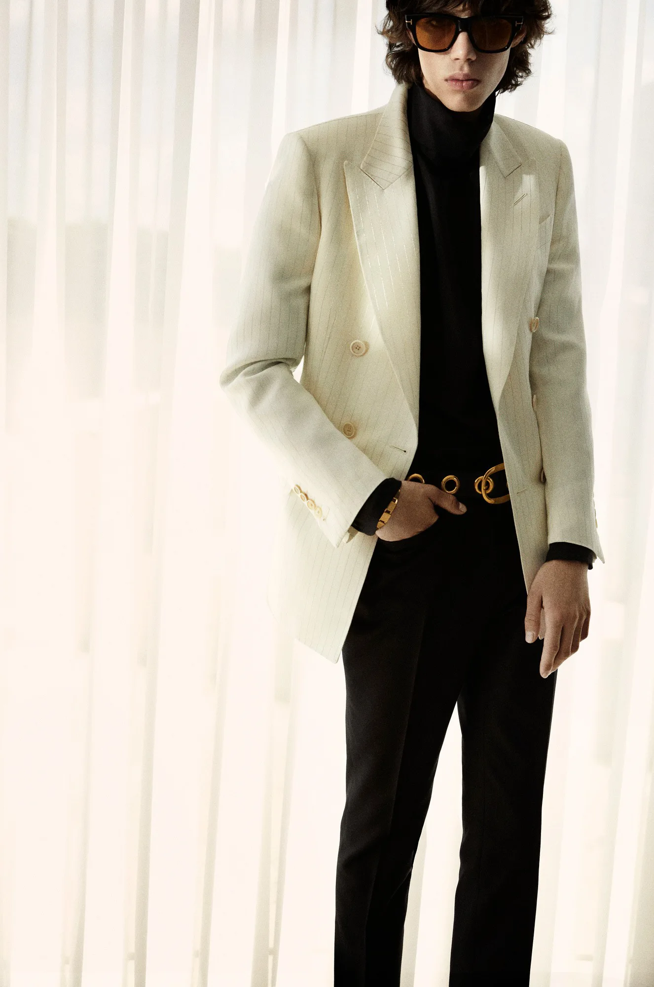 Krem tonlarında blazer ve siyah monokrom kombinle kullanılan gold tokalı kemer, erkek stilinde modern lüks ve güçlü silüet vurgusunu öne çıkarıyor.