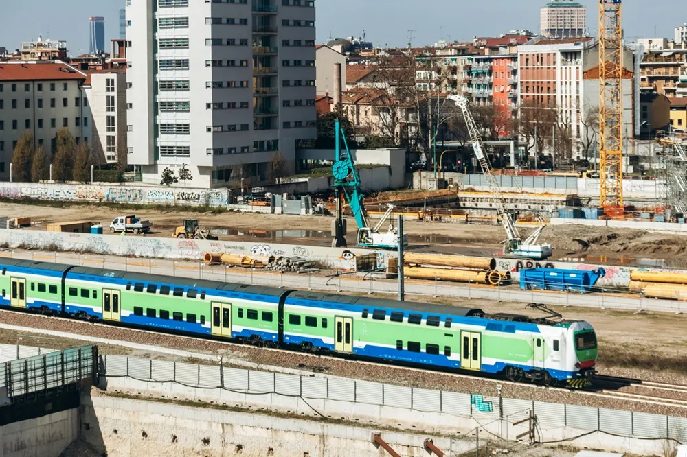 Milano’da Fondazione Prada yakınındaki olimpiyat köyü inşaat alanının önünden geçen Trenord treni, Milano Cortina 2026 hazırlıklarını gösteriyor.