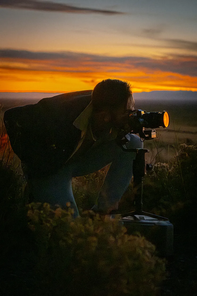 Gün batımında tripod üzerinde analog fotoğraf makinesiyle çekim yapan kişi