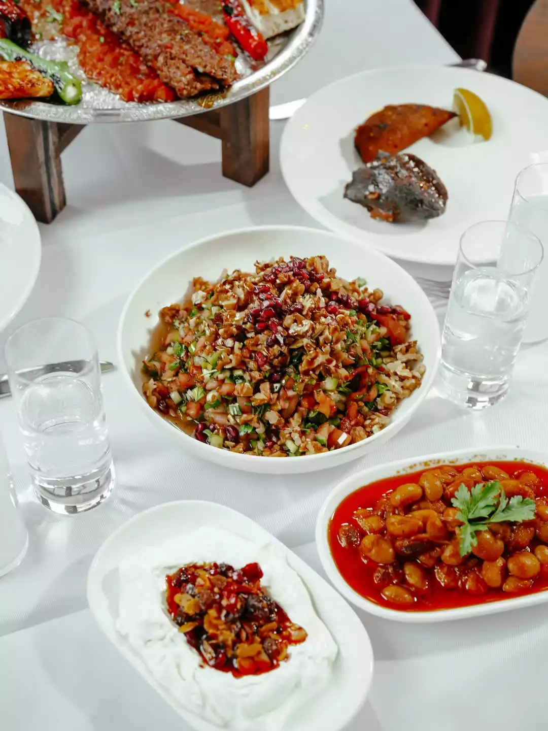 Beyaz bir masa örtüsü üzerinde; Adana kebaba benzeyen ızgara etler, biber ve acılı ezmeli gümüş bir tepsi, bol cevizli ve nar taneli gavurdağı salatası, kuru meyve ve cevizle zenginleştirilmiş yoğurtlu bir meze, domates soslu barbunya pilaki ve limon dilimli ızgara et veya balık gibi geleneksel Türk mutfağının zengin lezzetleri sergileniyor.