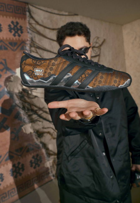 Benji Tokyo x adidas Originals sneaker iş birliği, desenli spor ayakkabı modeli elde tutulurken çekilmiş ürün fotoğrafı.