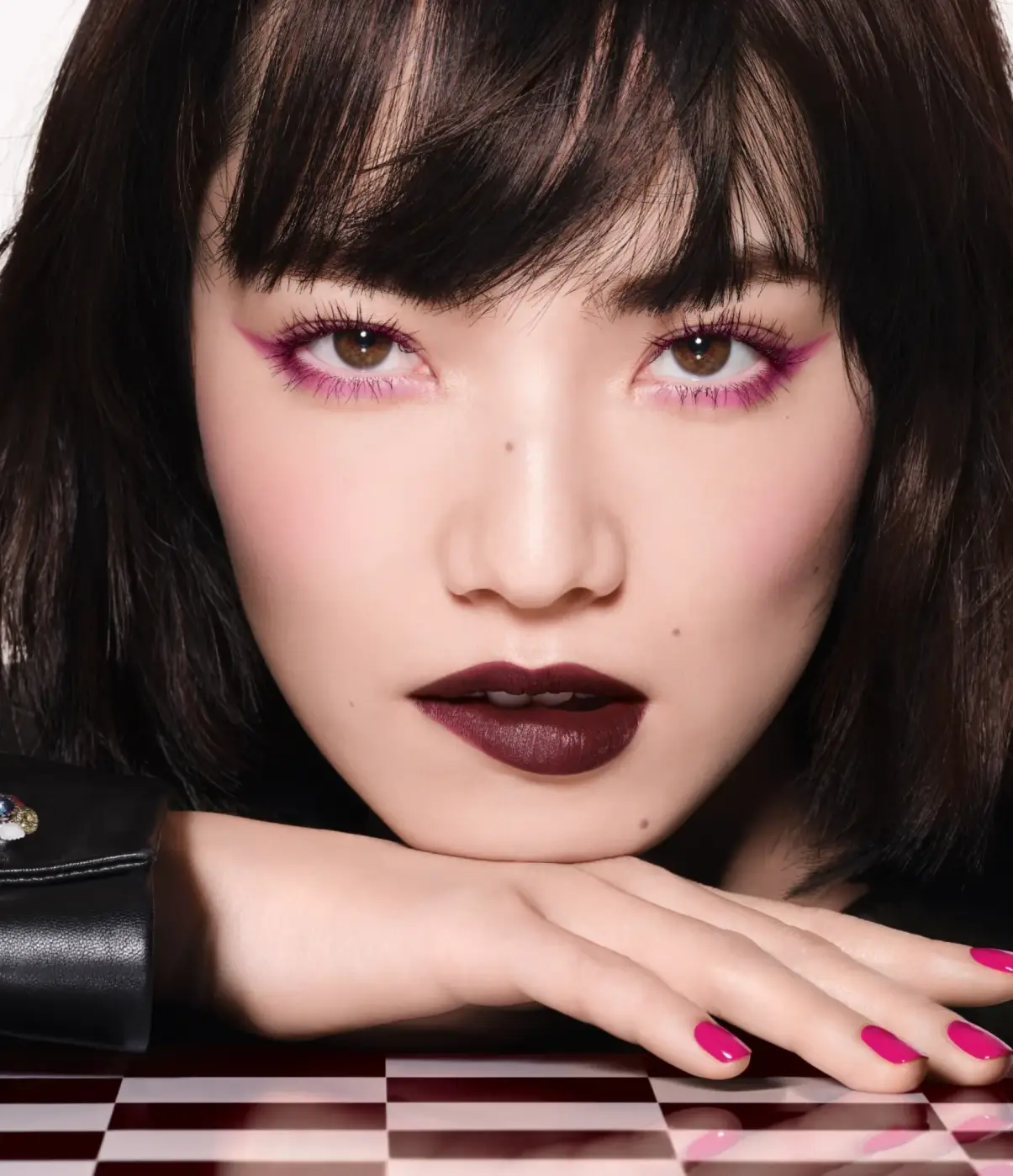 Chanel'in bordo maskara, göz kalemi ve ruju ile dudağını ısırarak poz veren kadın model