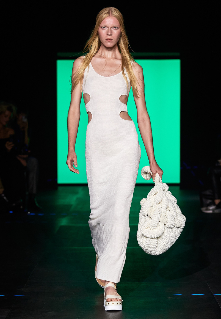 Chloé İlkbahar/Yaz 2023 koleksiyonunda yanları cut-out detaylı beyaz elbise ve el örgüsü çantayla sürdürülebilir, doğal ve feminen moda yaklaşımı.