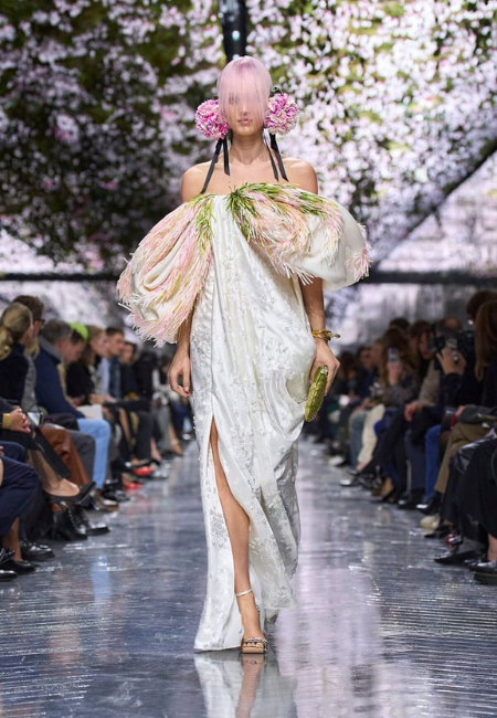 Dior 2026 couture defilesinde tüy detaylı omuz silüeti ve pastel tonlarla yorumlanan romantik haute couture elbise.