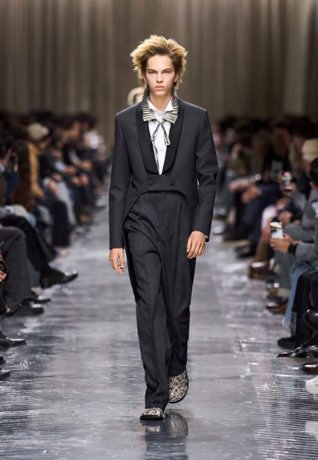 Dior 2026 sonbahar kış erkek defilesi, siyah takım elbise ve fiyon detaylı gömlek ile podyum stili.