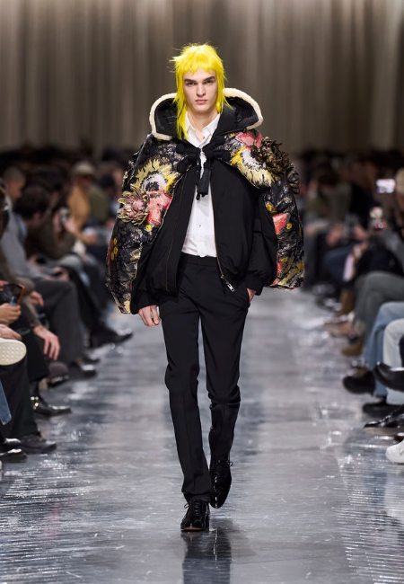 Dior 2026 sonbahar kış erkek defilesi, çiçek işlemeli puffer ceket ve siyah takım pantolon kombini.