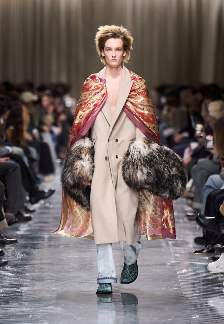 Dior 2026 sonbahar kış erkek giyim defilesi, bej palto ve desenli şal detaylı podyum stili.