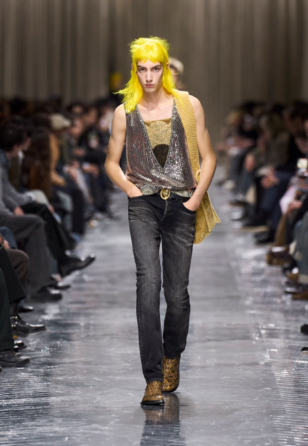 Dior 2026 sonbahar kış erkek giyim defilesi, metalik yelek ve koyu jean ile podyum görünümü.