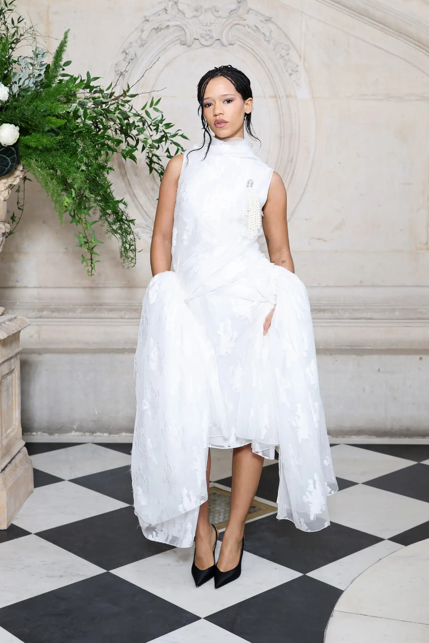 Taylor Russell Dior 2026 Couture defilesinde beyaz asimetrik elbise ve minimal şıklık.