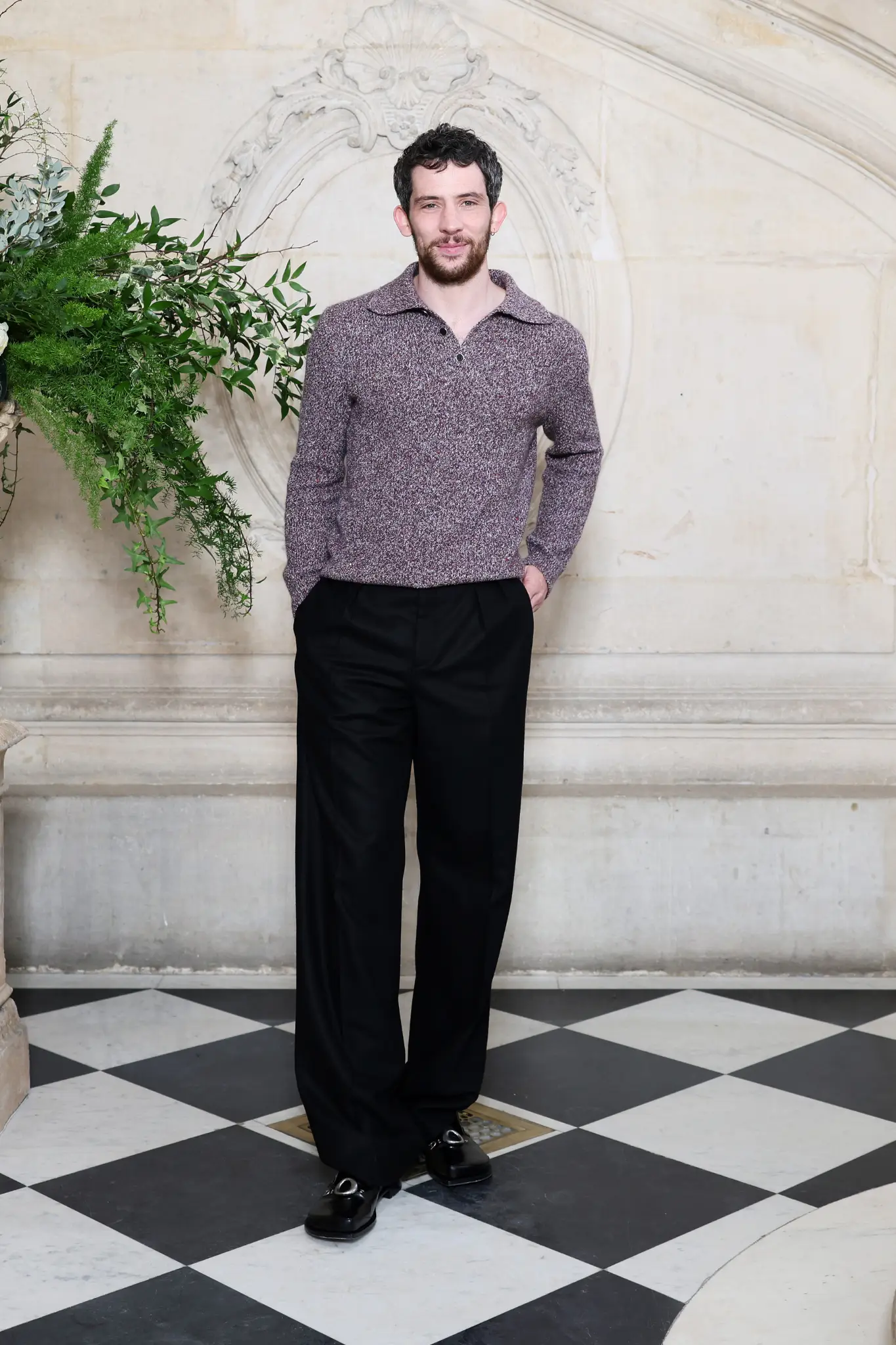 Josh O’Connor Dior 2026 Couture defilesinde bordo triko ve siyah pantolonla modern erkek stili.