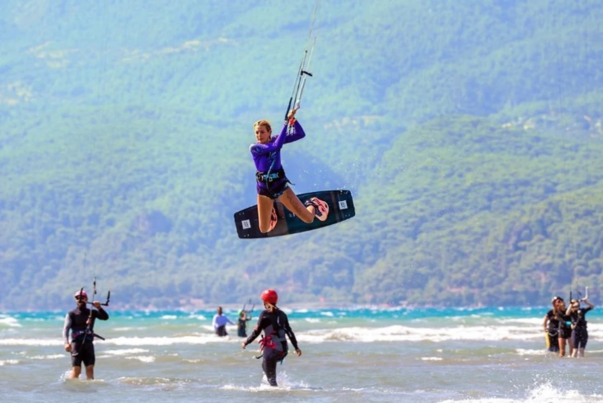 Türkiye’de sörf yapılacak yerler arasında öne çıkan Akyaka’da, masmavi deniz ve yeşil dağlar önünde havaya sıçrayan bir kitesurfçü.