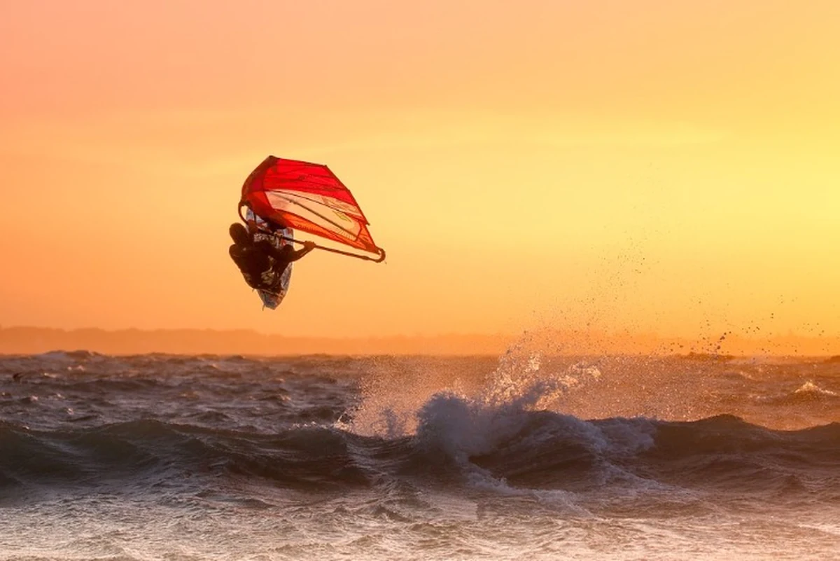 Türkiye’de sörf yapılacak yerler arasında rüzgârıyla öne çıkan Akyarlar’da, gün batımında dalgaların üzerinde sıçrayan bir windsurfçü.