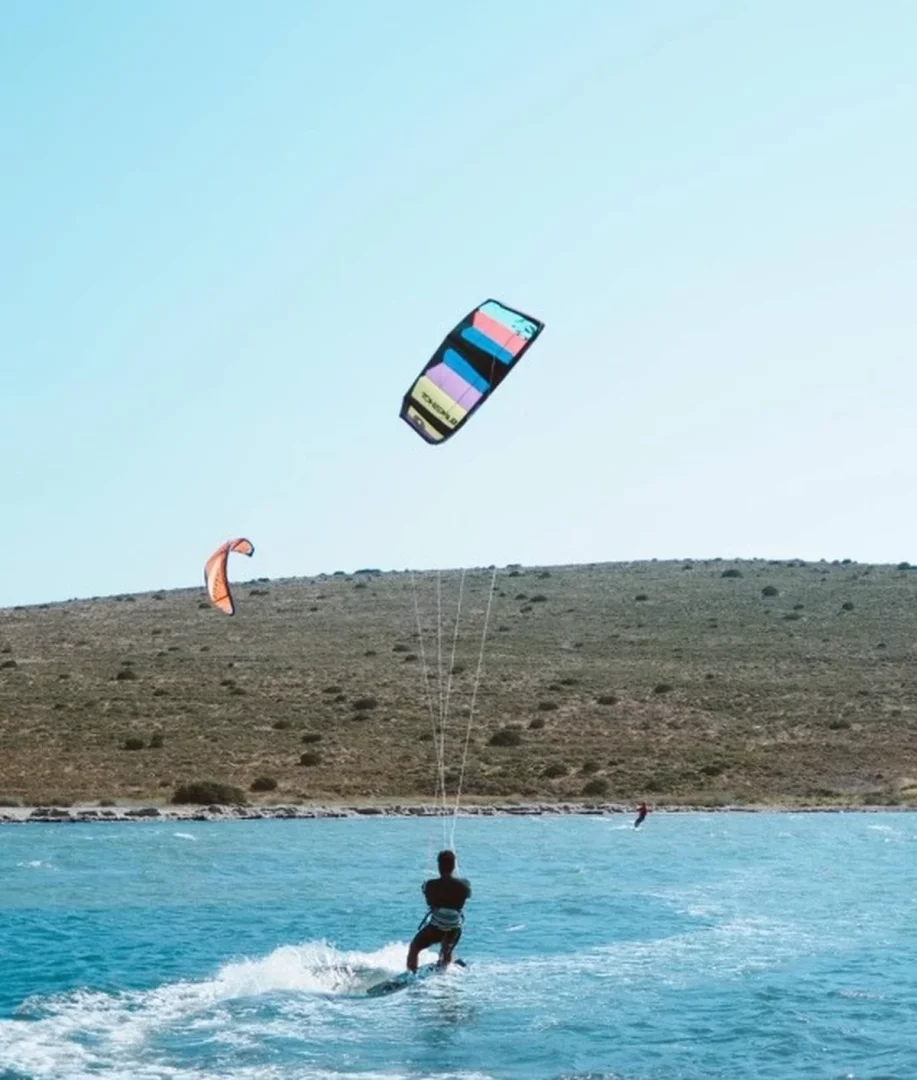 Alaçatı, Türkiye’de sörf yapılacak yerler arasında öne çıkarken berrak mavi denizde renkli uçurtmasıyla ilerleyen bir kitesurfçü görülüyor.