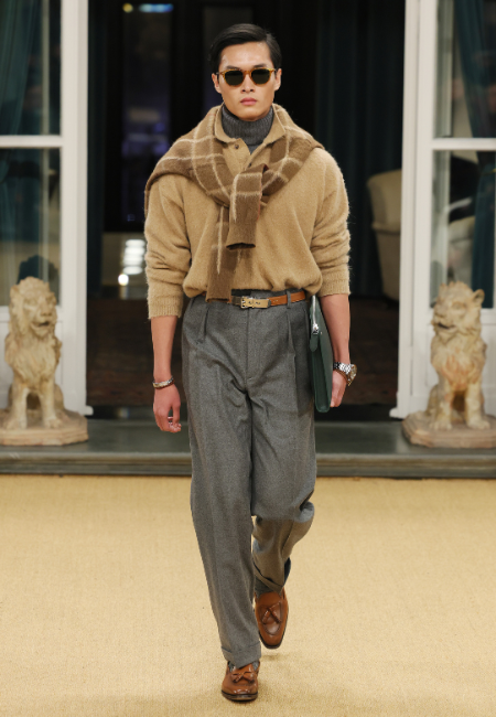 Ralph Lauren 2026 erkek moda haftası bej triko kazak, omuzda şal atkı, gri pileli pantolon ve kahverengi loafer ile klasik şıklık.