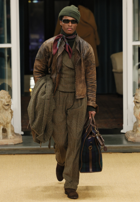 Ralph Lauren 2026 erkek koleksiyonu kahverengi deri ceket, örgü triko katmanlar, şal detaylı aksesuar ve yün pantolon ile vintage look.