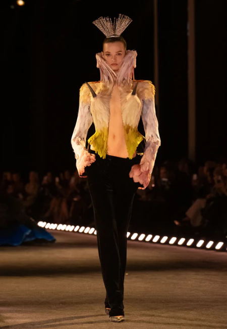 Schiaparelli 2026 haute couture defilesi, avangart omuz detaylı transparan üst ve siyah pantolon kombini.