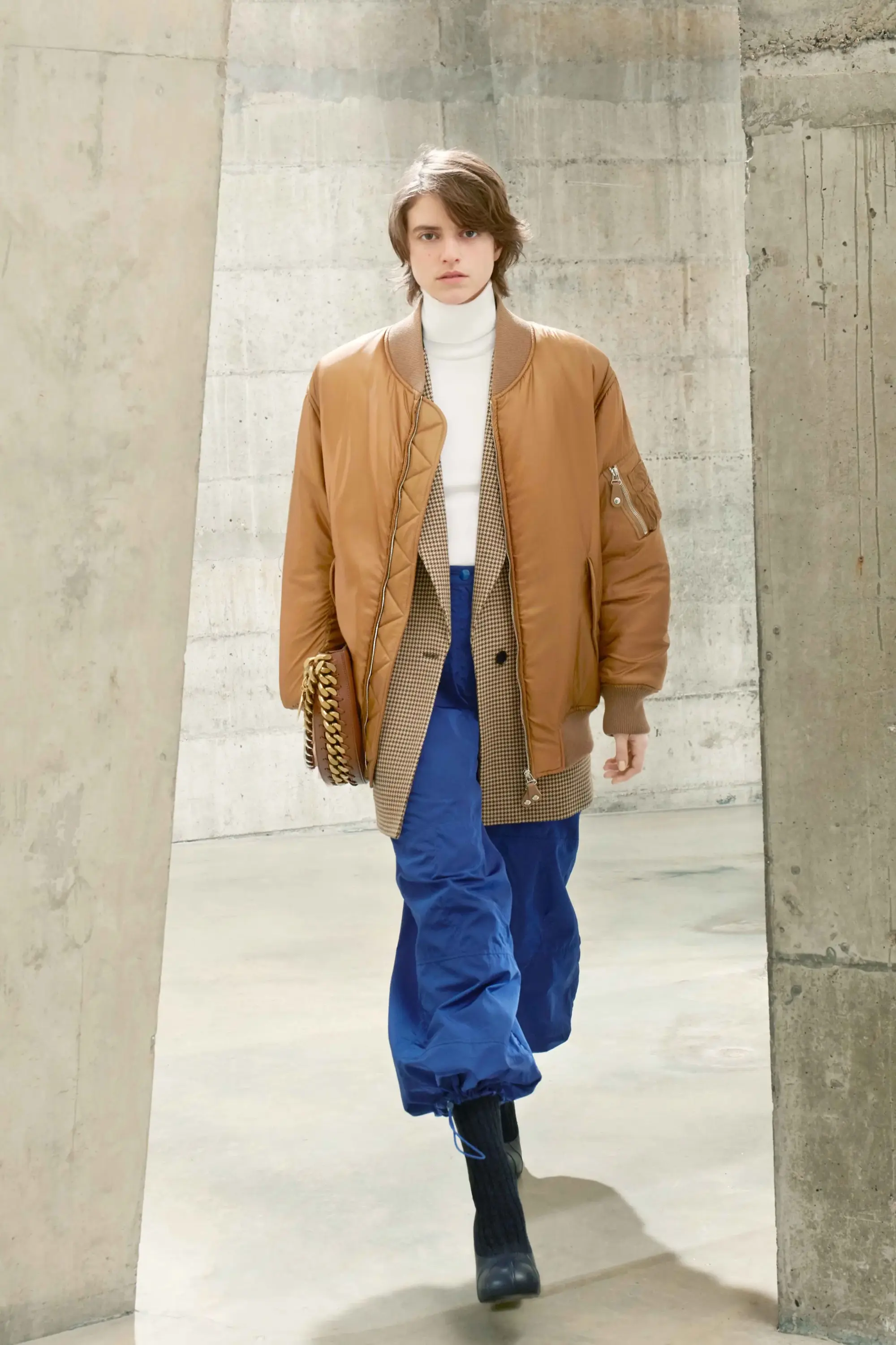 Stella McCartney Sonbahar/Kış 2021 koleksiyonunda kahverengi bomber ceket, mavi pantolon ve minimalist silüetle çağdaş lüks moda yorumu.