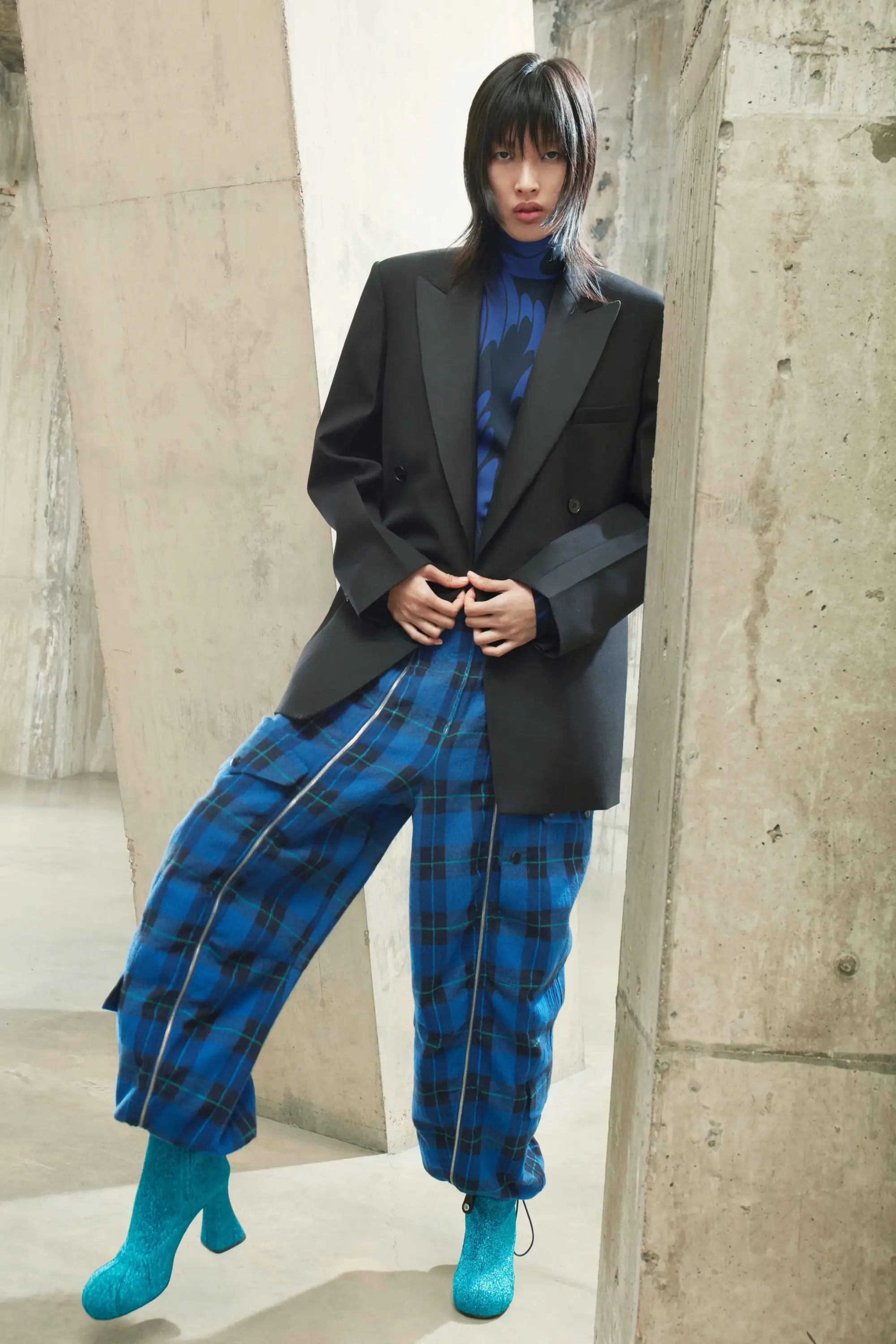 Stella McCartney Sonbahar/Kış 2021 defilesinden siyah ceket, mavi ekose pantolon ve parlak botlarla modern tailoring yorumu.