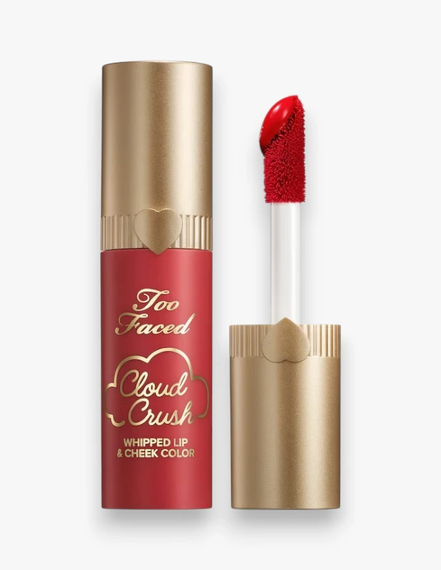 Too Faced Cloud Crush Whipped Lip & Cheek Color adlı ürünün mat kırmızı ambalajı, altın rengi kapağı ve yoğun kırmızı rengindeki aplikatörüyle beyaz fonda dikey duruşunu gösteren bu fotoğraf, dudak ve yanak rengi arayanlar için cazip bir seçenek sunuyor.