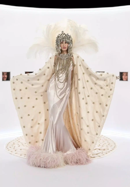 Haute couture podyumunda sergilenen, altın ruff yaka detaylı fuşya pelerin, işlemeli mini elbise ve dramatik kol hacimleri.