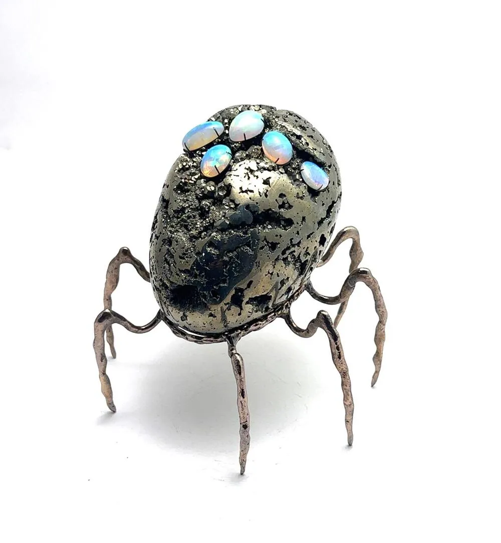 Opal taşlı, pirit yüzeyli gövdesi ve ince metal ayaklarıyla örümceği andıran heykel formu, Ali Rıza Akdolu’nun “Aliens” serisinden bir eser.