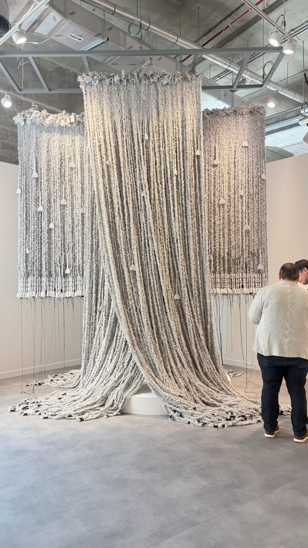 Art Basel Katar’da Bouthayna Al Muftah’a ait, tavandan sarkarak zemine yayılan yoğun dokulu ip ve tekstil yerleştirmesi.